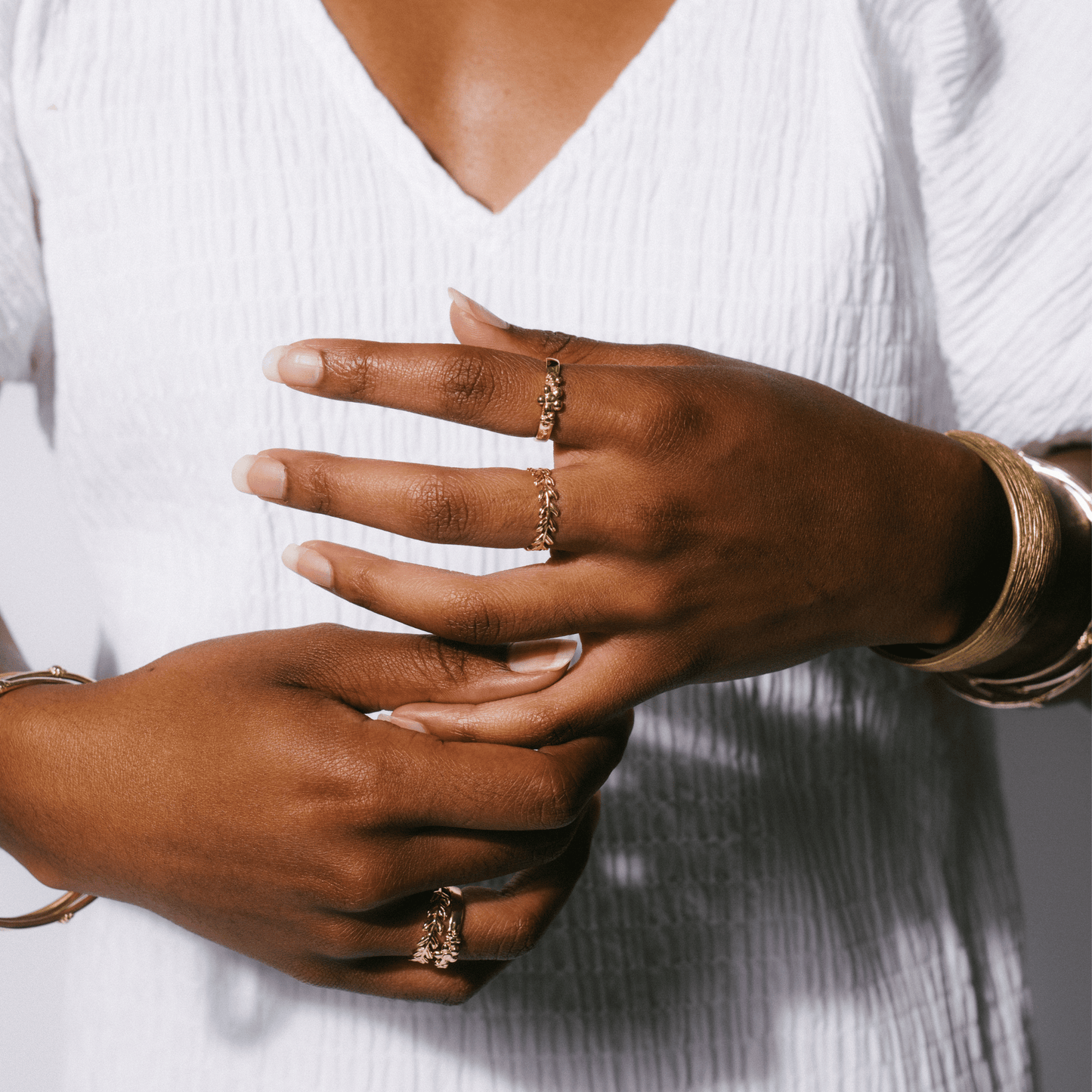 A golden band and other jewelry on the hand of a woman.