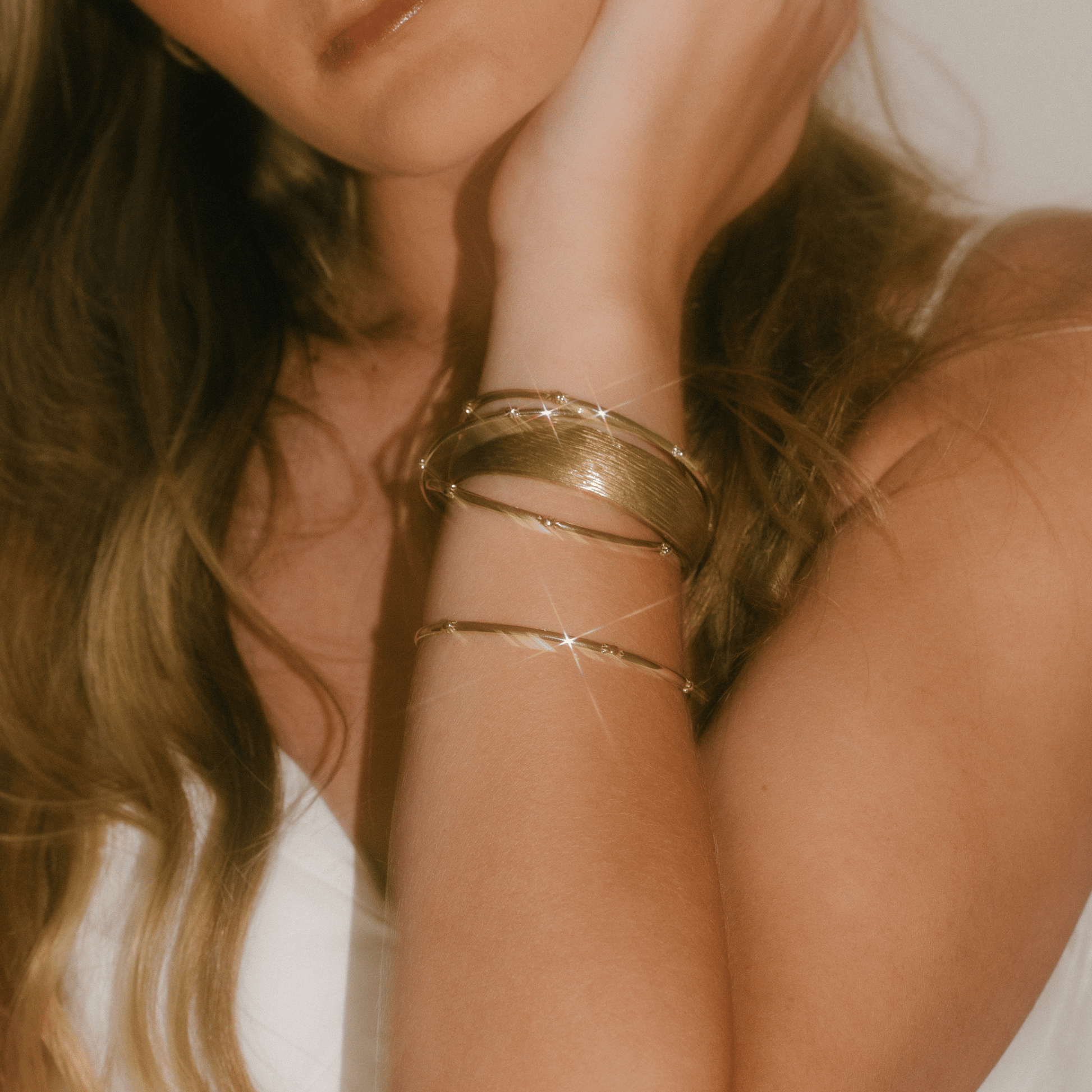 The hydrangea bangle is stacked on a woman's wrist with other bangles.