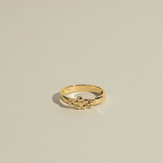 The Frida ring is gold and adorned with three flowers.