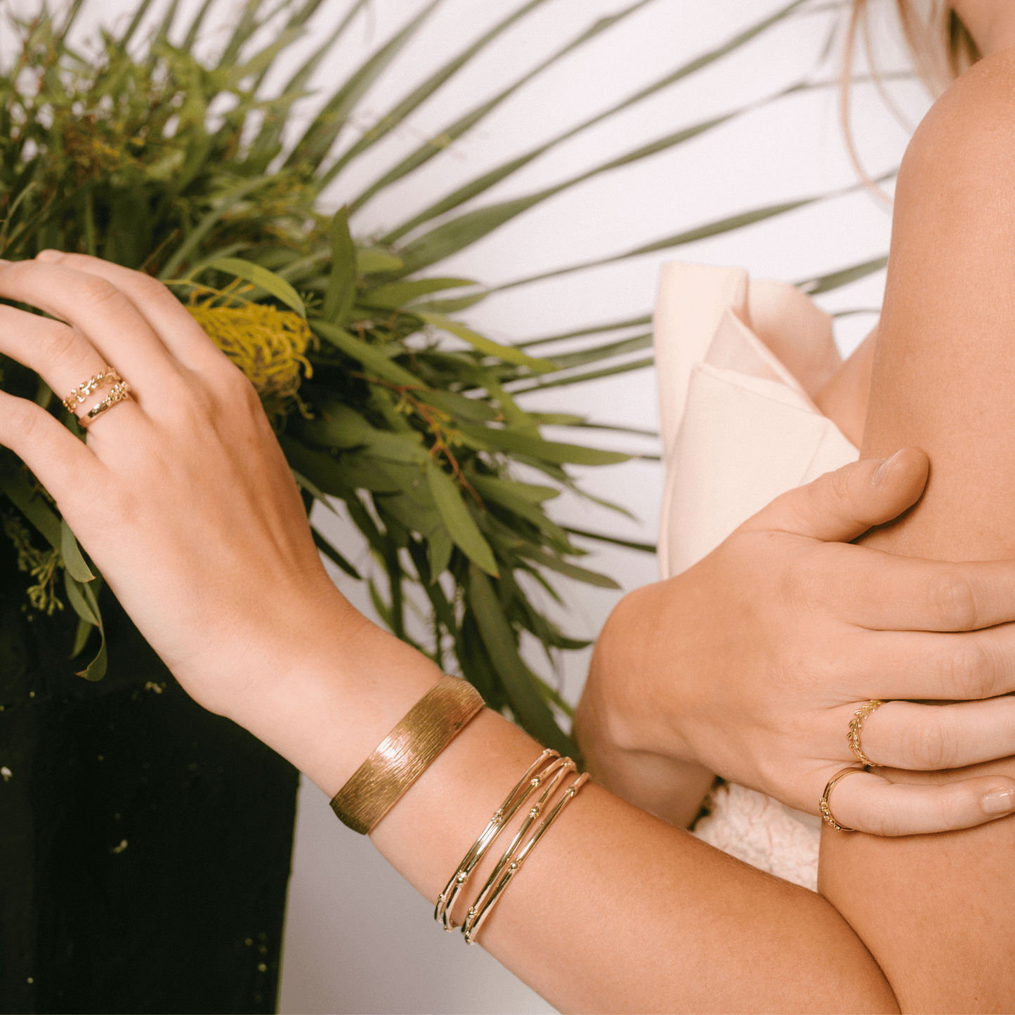 The hydrangea bangle is stacked on a woman's wrist with other bangles.
