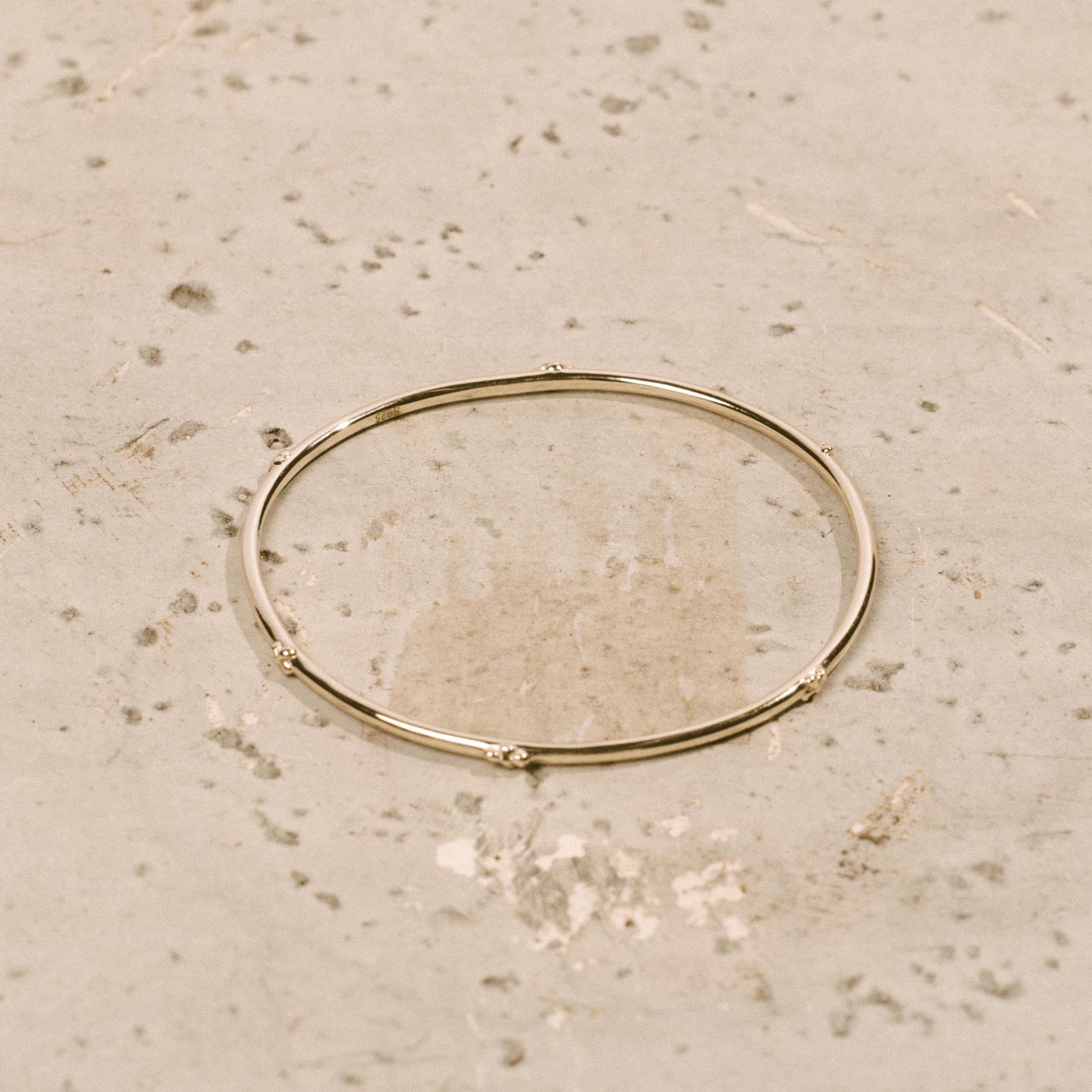 The hydrangea bangle is a thin golden bangle adorned with hydrangea flowers.