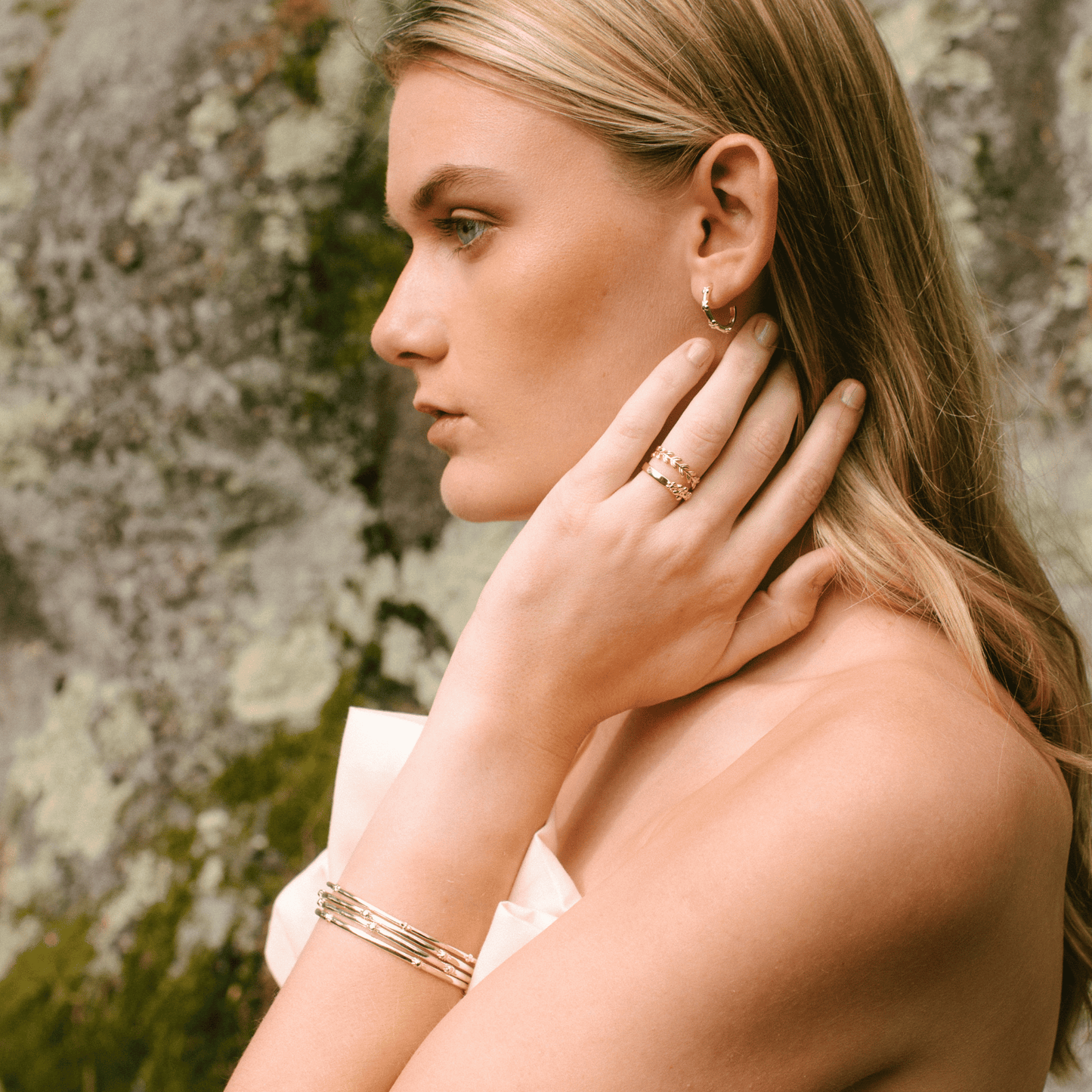 The hydrangea bangle is stacked on a woman's wrist with other bangles.