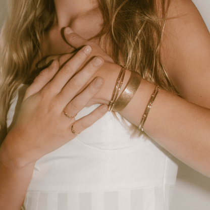 The sunflower bangle stacked with other golden bangles on a woman's wrist.