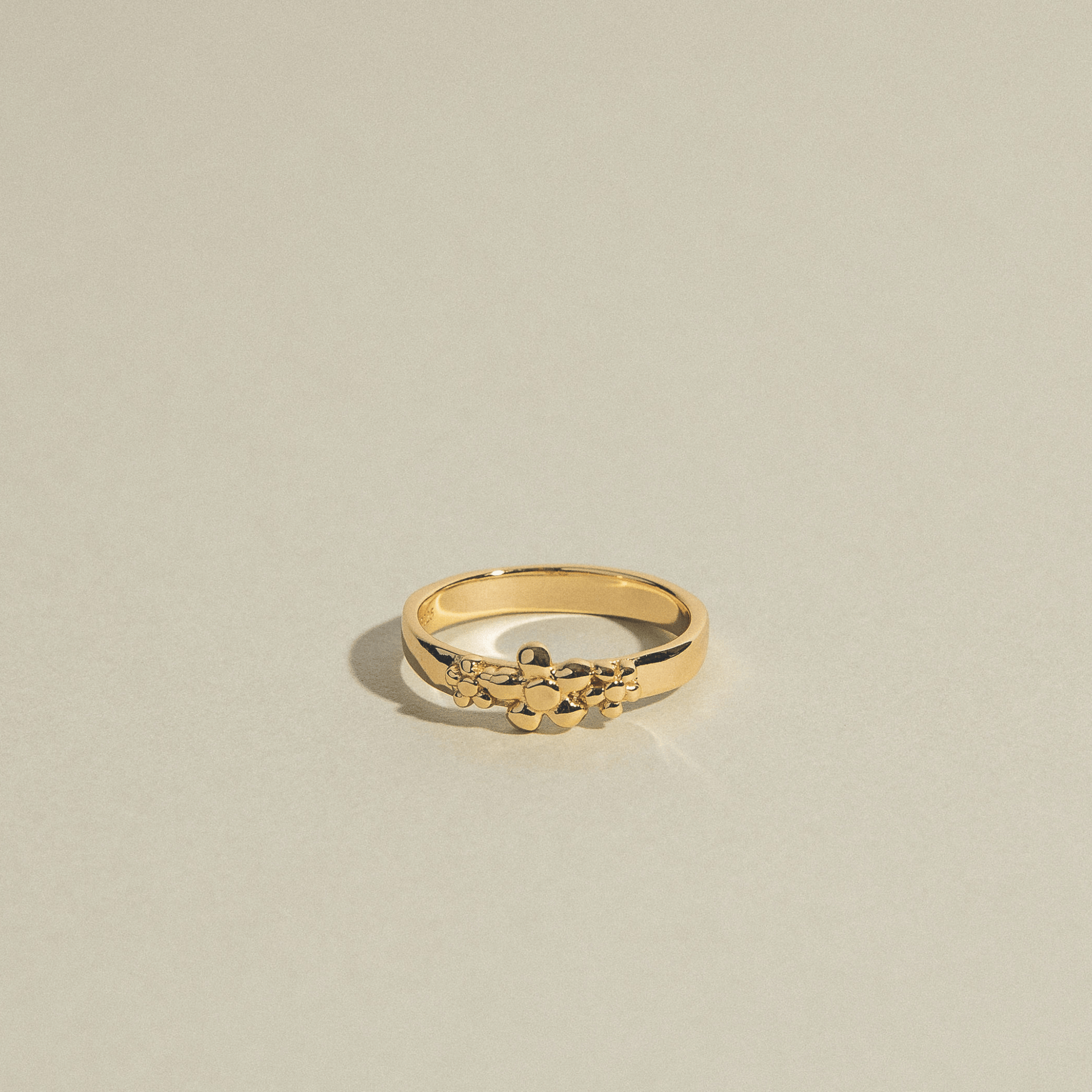The Frida ring is gold and adorned with three flowers.