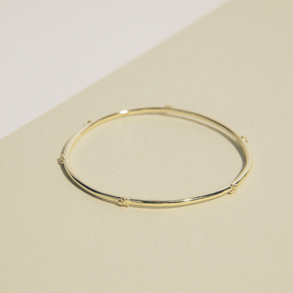 The hydrangea bangle is a thin golden bangle adorned with hydrangea flowers along the perimeter.