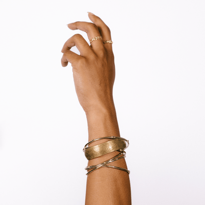 The hydrangea bangle is stacked on a wrist in the air with other bangles.