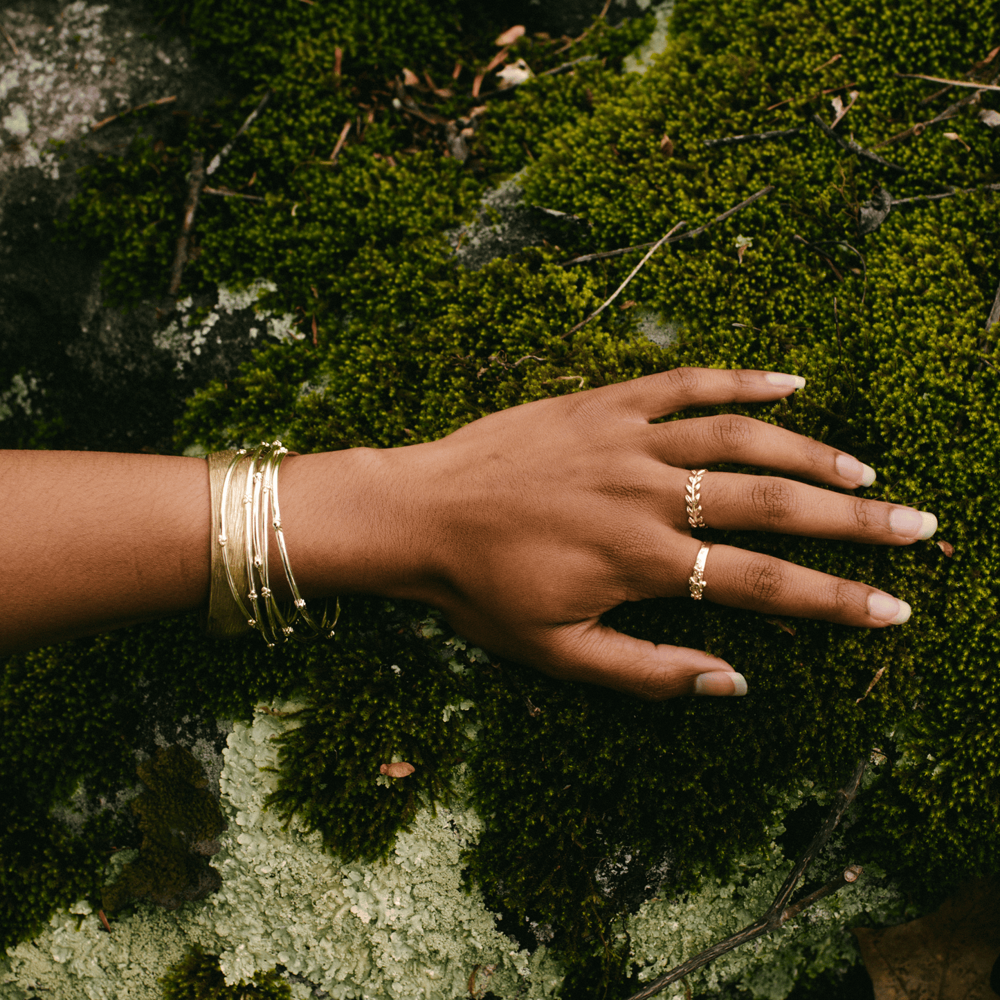 A golden band and other jewelry on the hand of a woman.